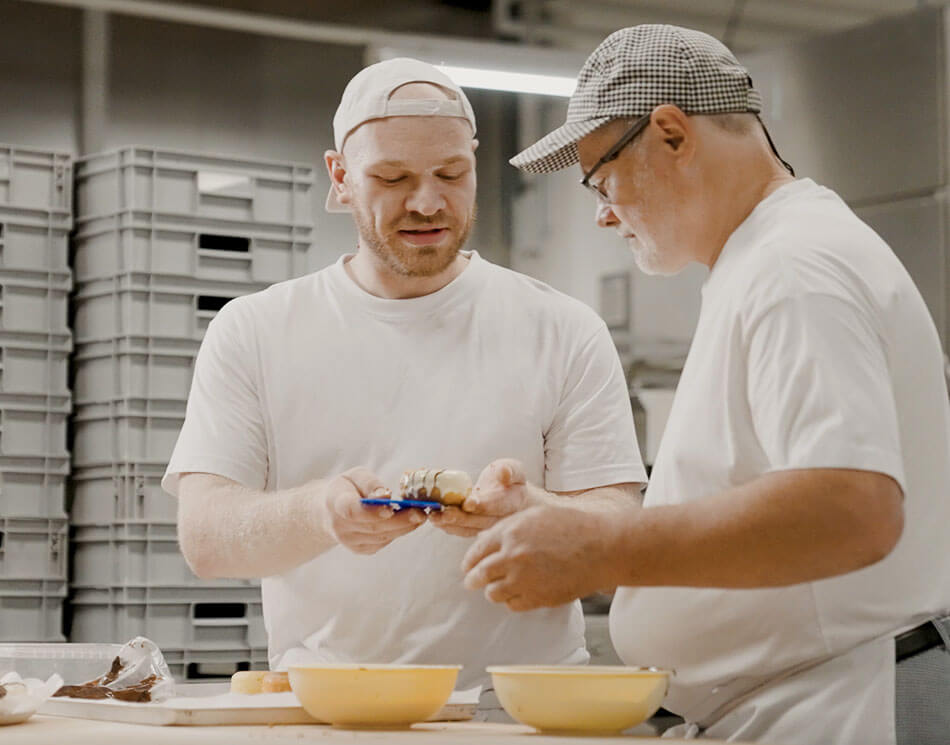 Ausbilder erklärt Azubi das Bäcker-Handwerk in der Back-Stube der Bäckerei Meyer