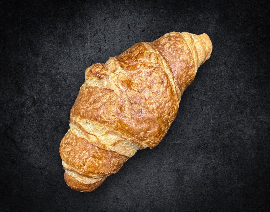Ein Croissant mit schichtiger Oberfläche. Es ist goldbraun und gebogen.