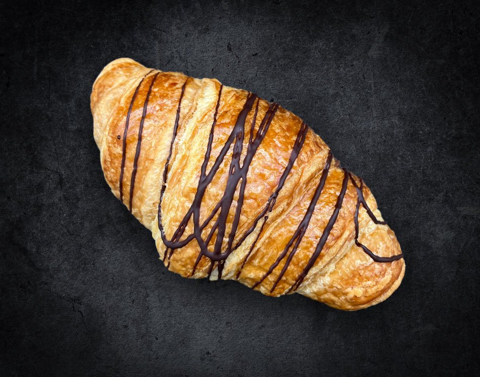 Ein Nougat-Croissant mit dunklen Streifen. Es ist goldbraun und gebogen.