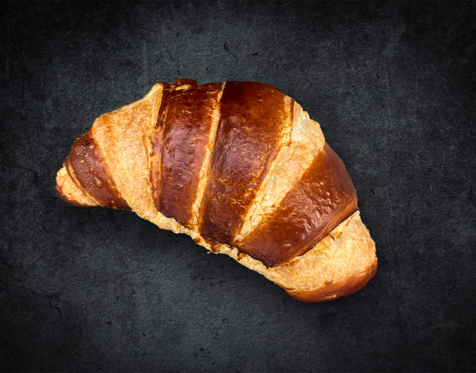 Ein Butter-Laugen-Croissant mit Einschnitten. Es ist goldbraun und gebogen.