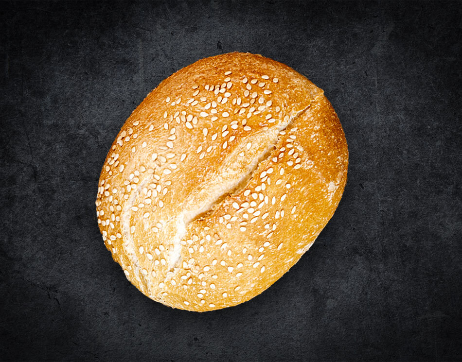 Ein Sesam-Brötchen mit weißen Sesam-Körnern. Es ist goldbraun und rund.