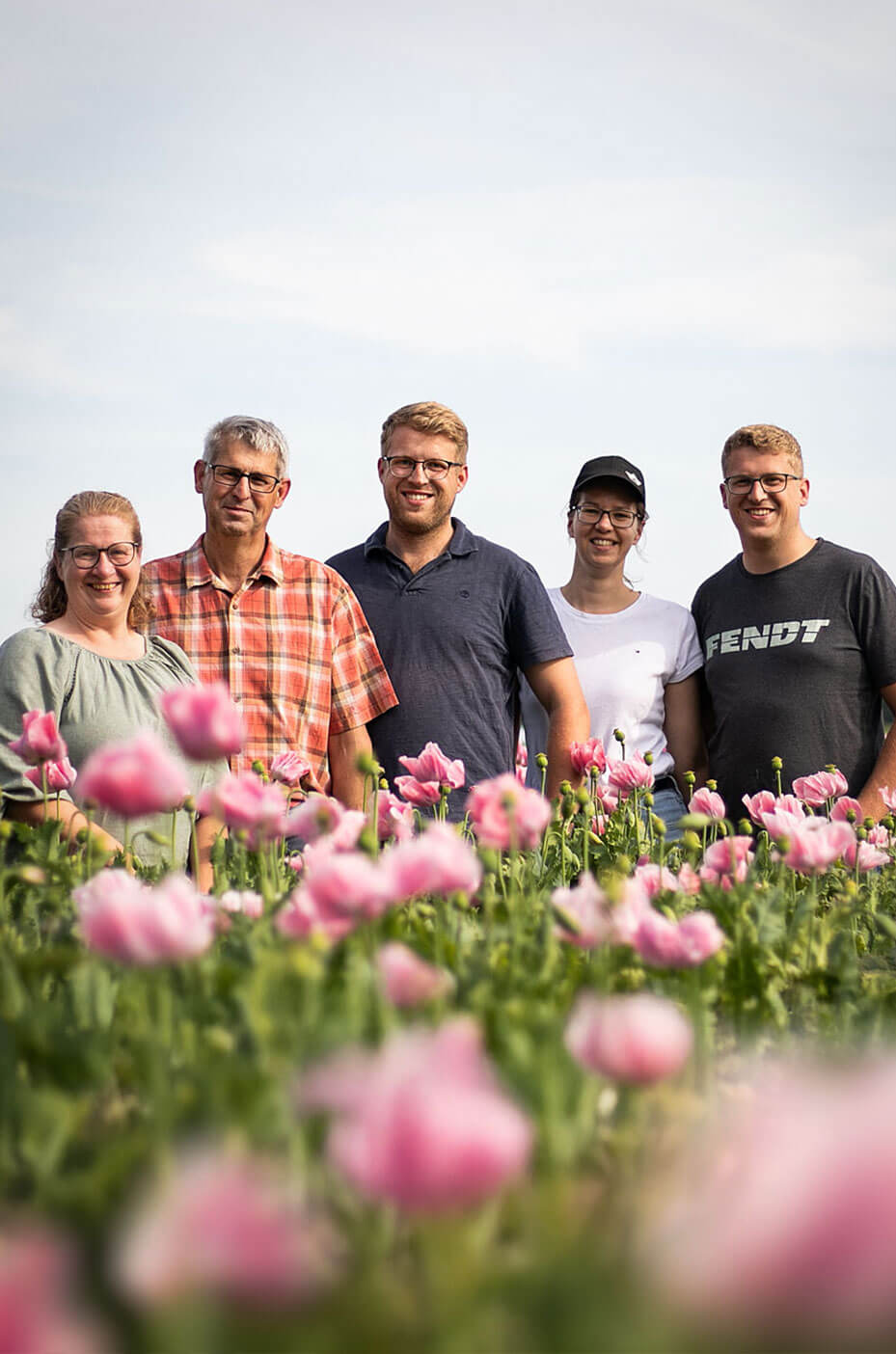 Familie Behn zwischen rosa blühenden Mohnpflanzen auf einem Feld - regionaler Partner der Heidebäckerei Meyer