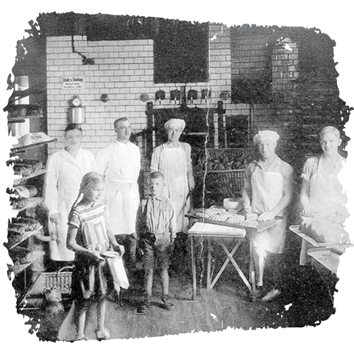 Unsere Anfänge: Familie Meyer in den frühen Jahren der Bäckerei in traditioneller Bäckerkleidung